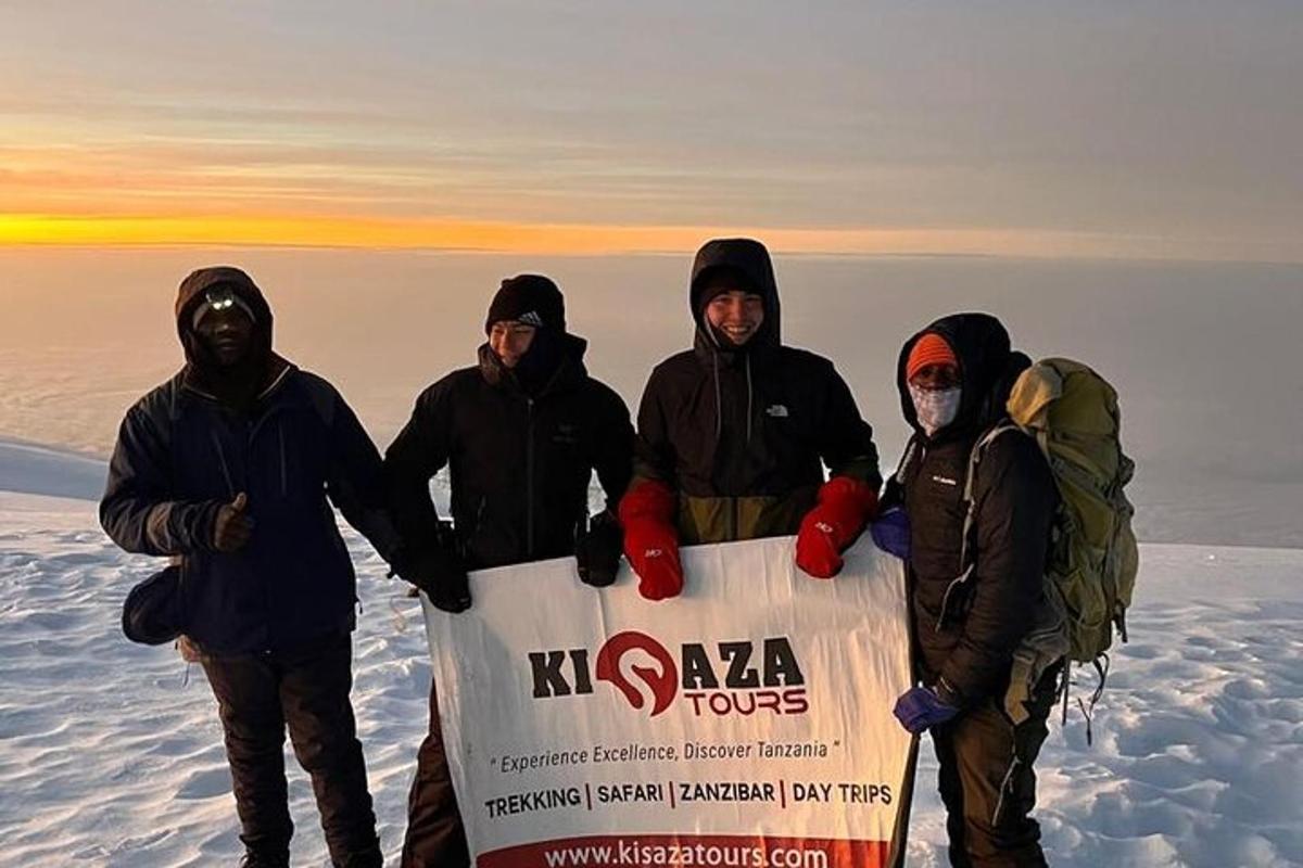 um grupo de pessoas segurando uma placa no topo de uma montanha