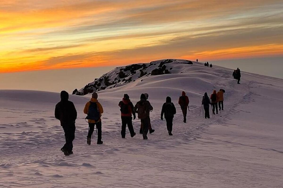 um grupo de pessoas caminhando na neve ao pôr do sol