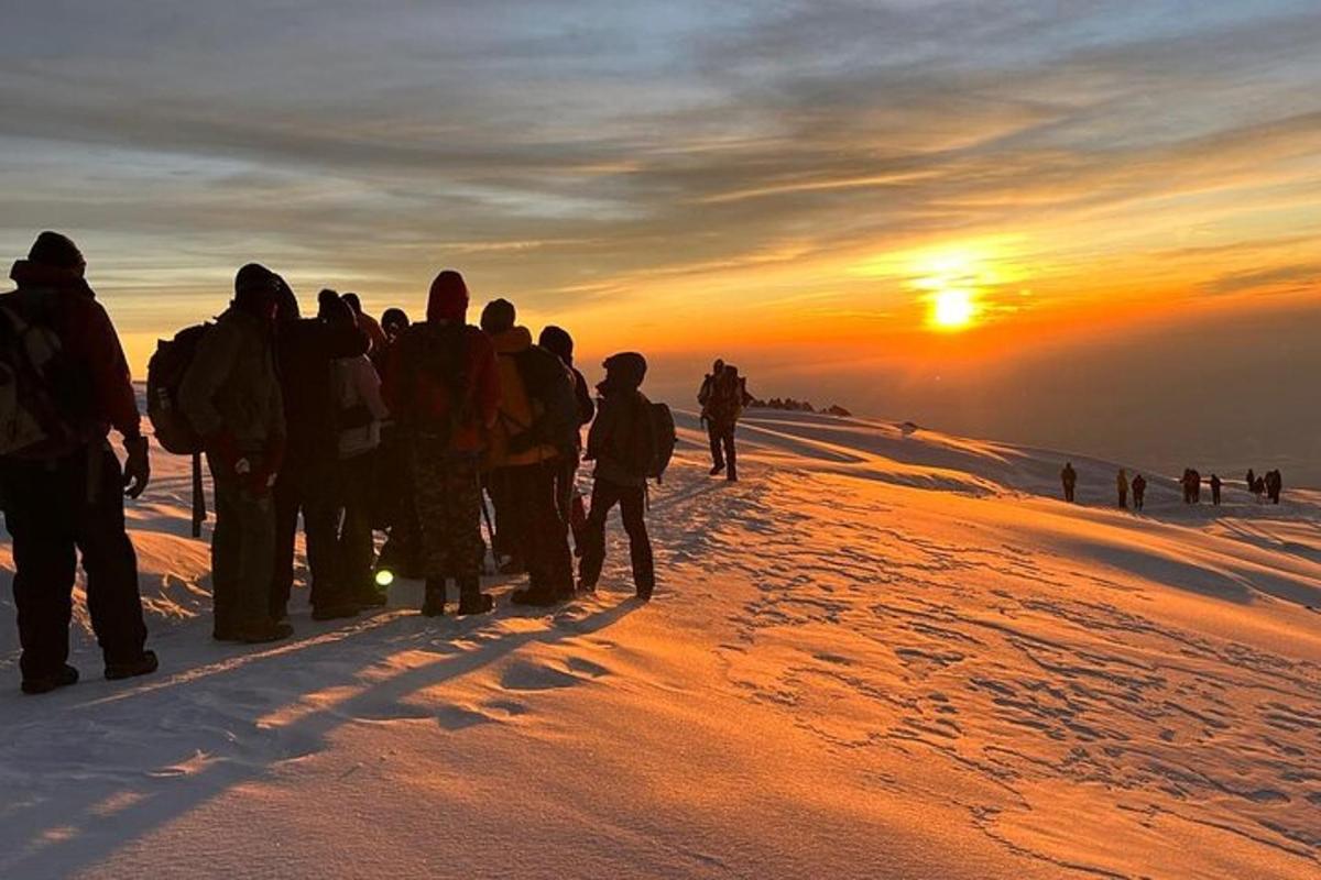 um grupo de pessoas em pé em uma montanha observando o pôr do sol
