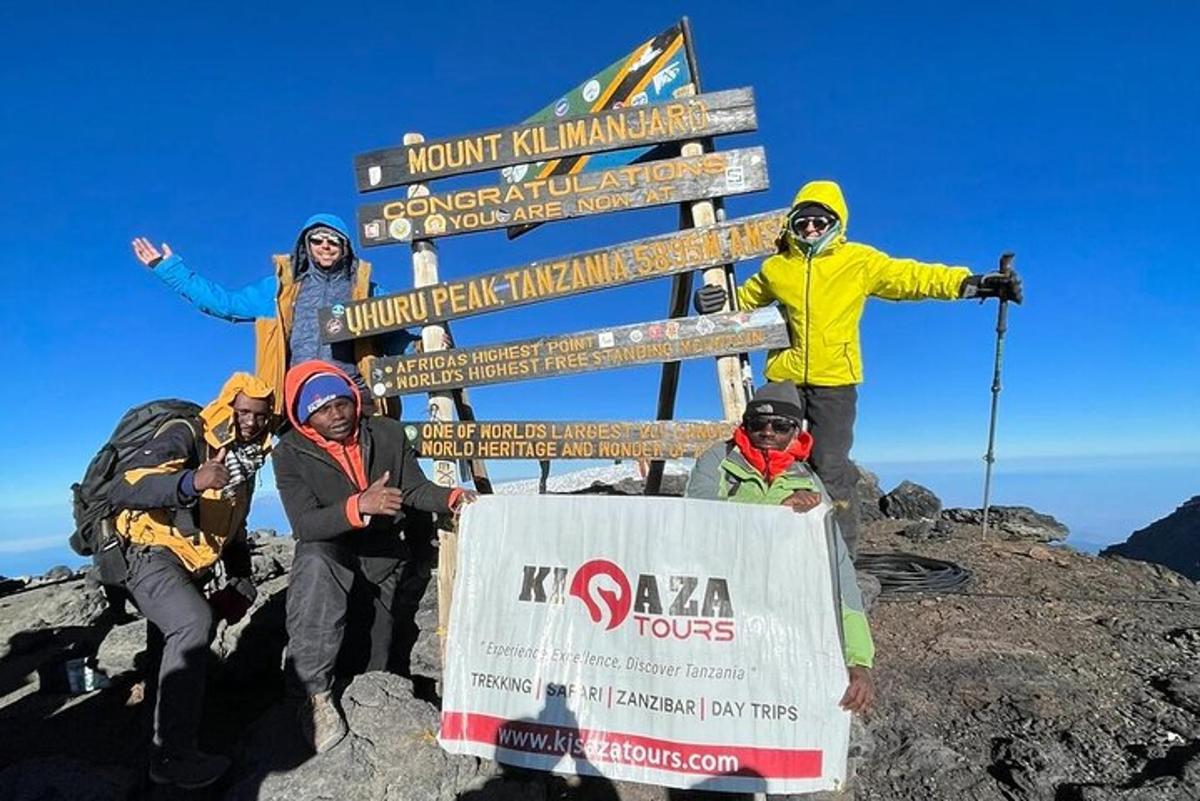 um grupo de pessoas em pé ao lado de uma placa em uma montanha