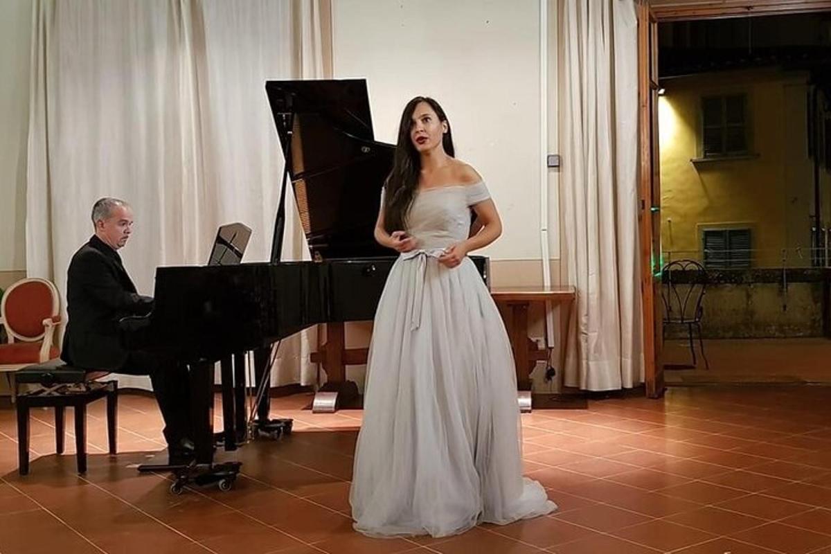 en kvinne i en hvit kjole som står ved siden av et piano
