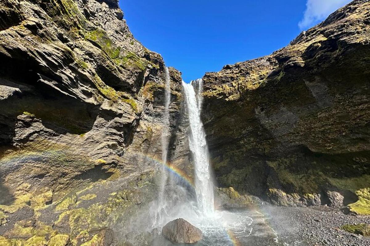 een waterval met een regenboog voor een berg