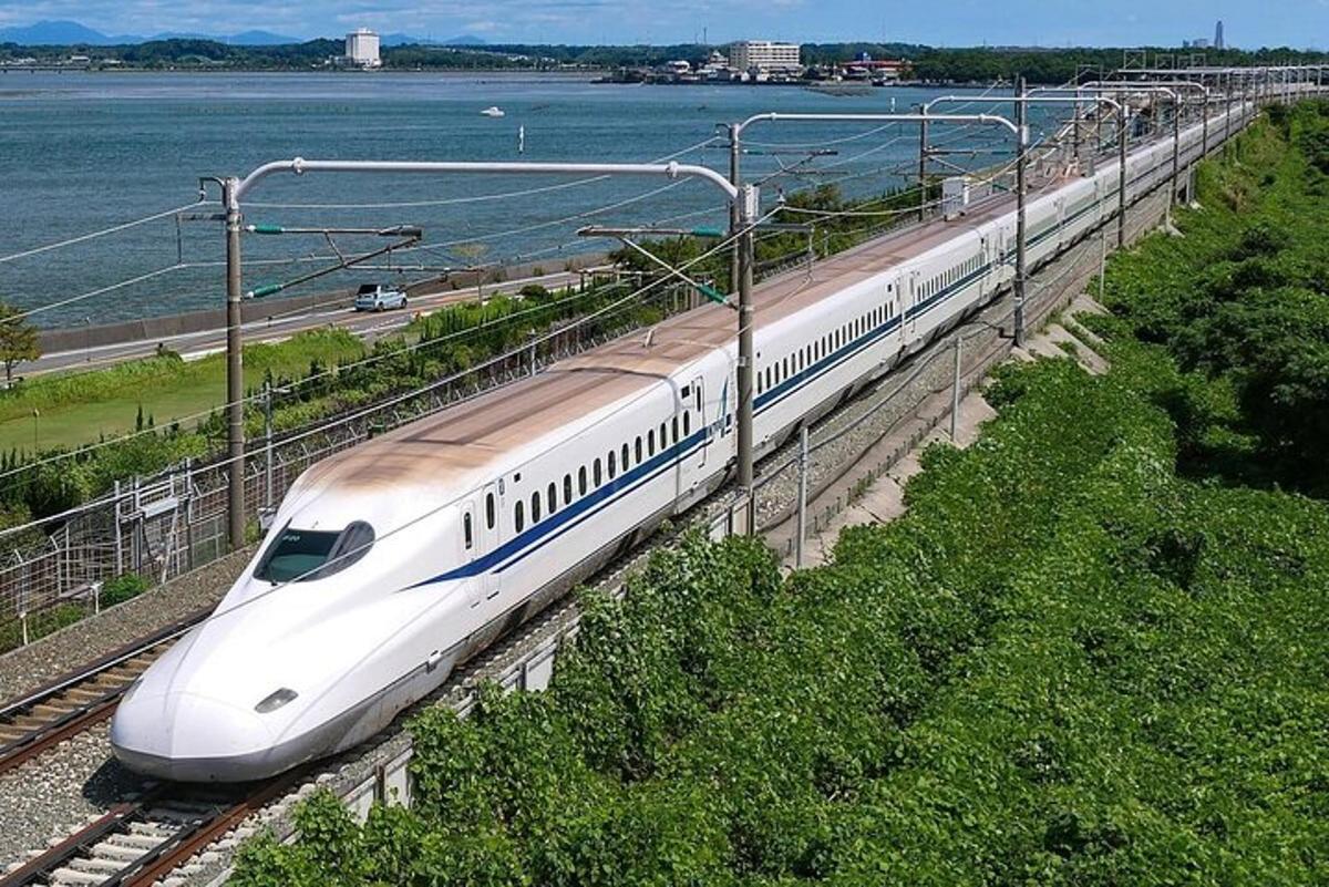 Un tren blanco está en las vías cerca del agua.