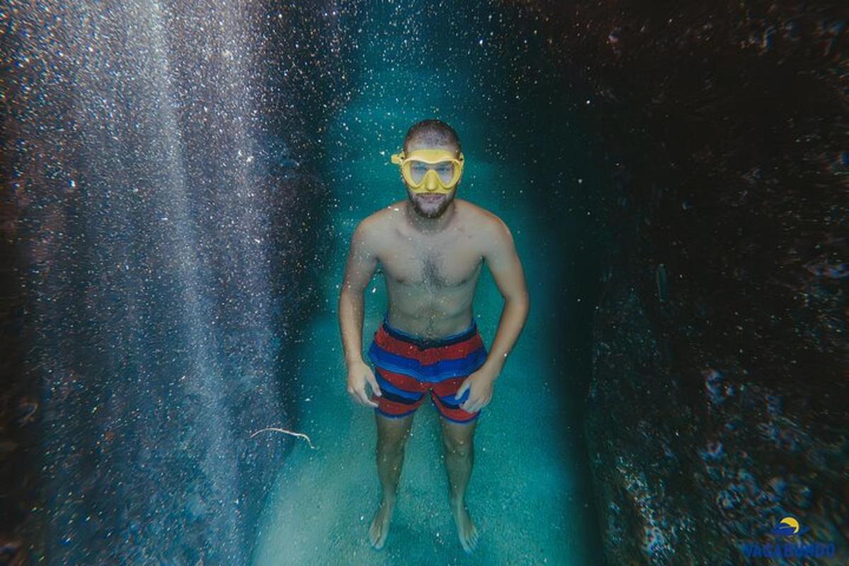 Un hombre parado en el agua debajo de una cascada.