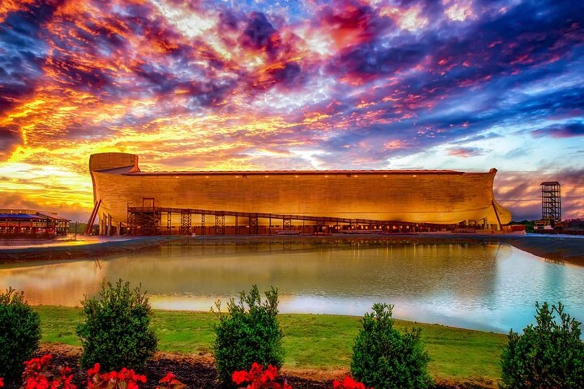 a large building in front of a lake with a sunset