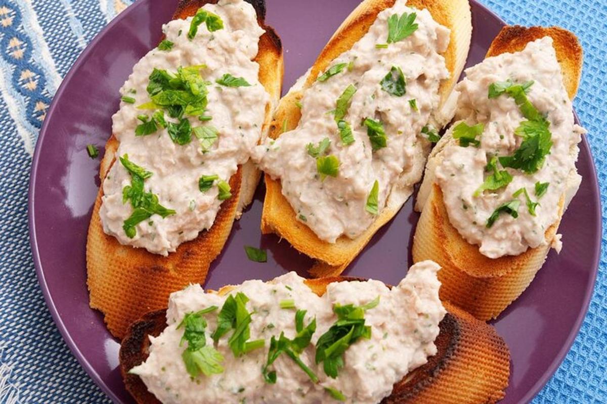 một đĩa màu tím với bốn miếng bánh mì kèm nước chấm