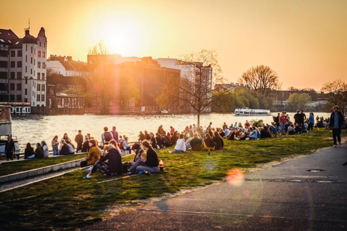 a crowd of people sitting on the grass near a river