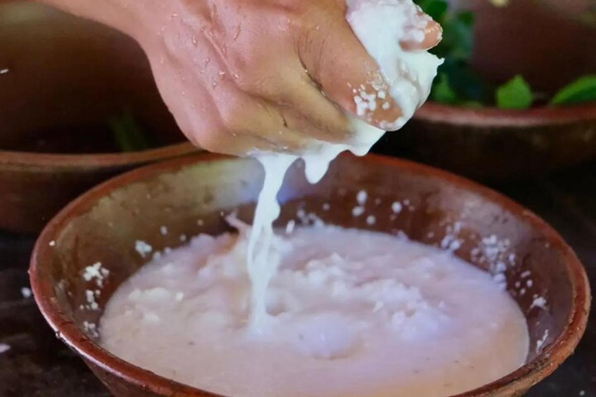 uma pessoa despejando leite em uma tigela de comida
