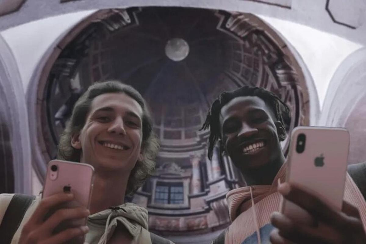 two men holding up their cell phones in front of a mirror