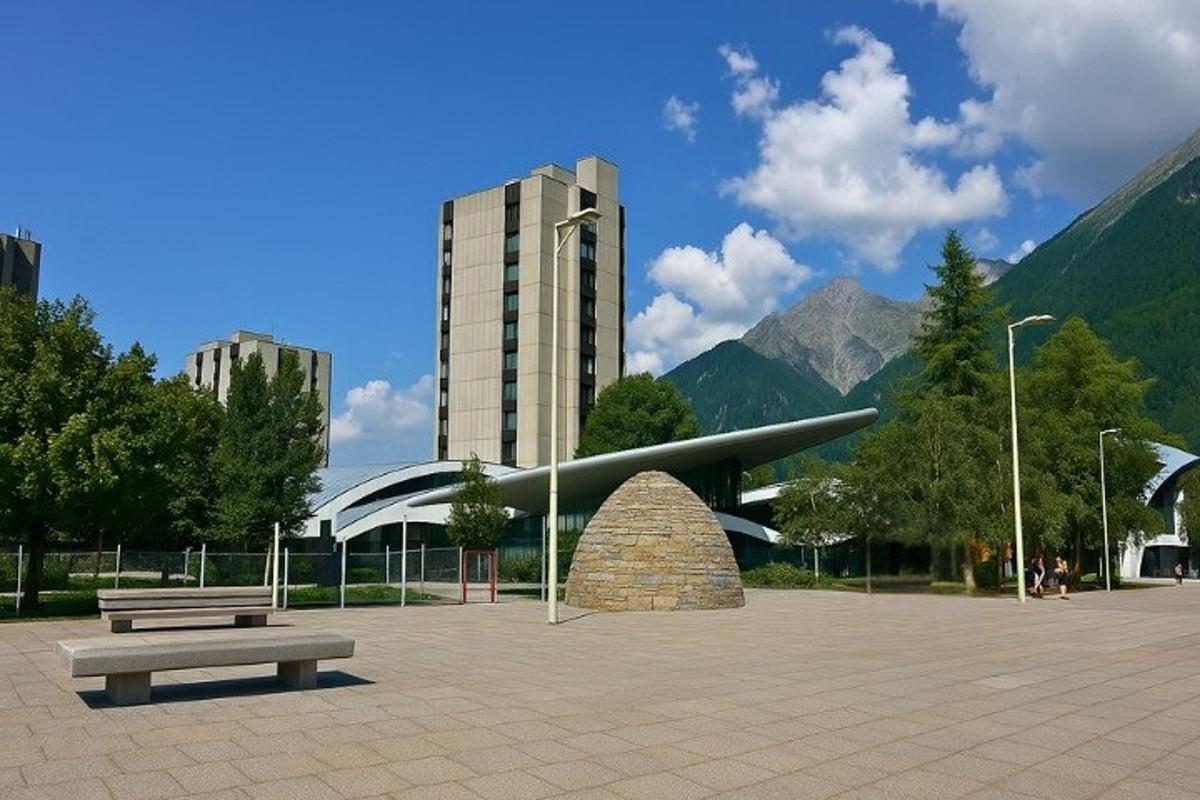 park s lavičkou, budovou a horami
