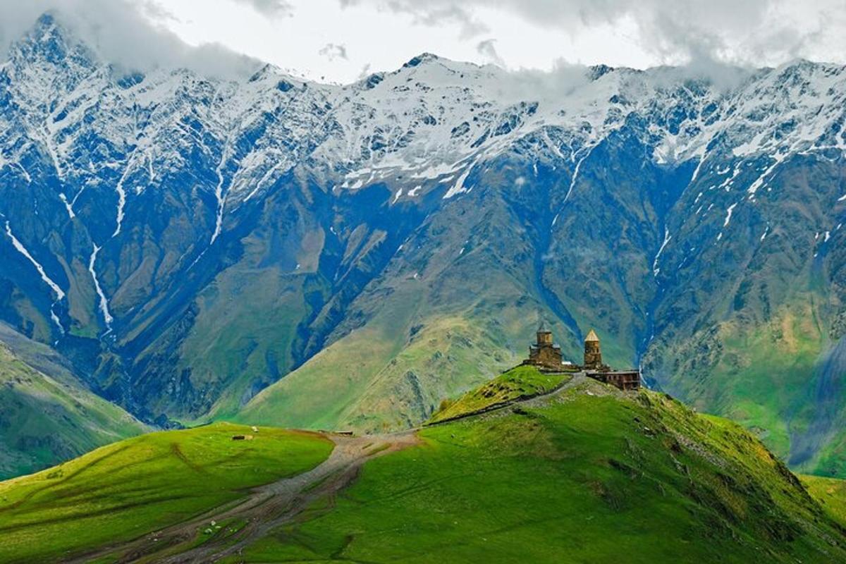 a house on top of a green hill with mountains