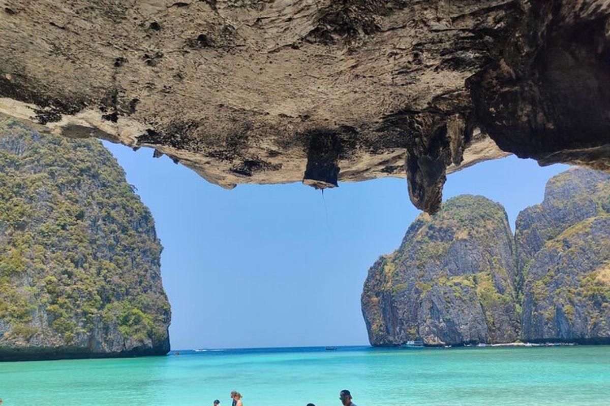 orang berdiri di pantai di bawah gua batu