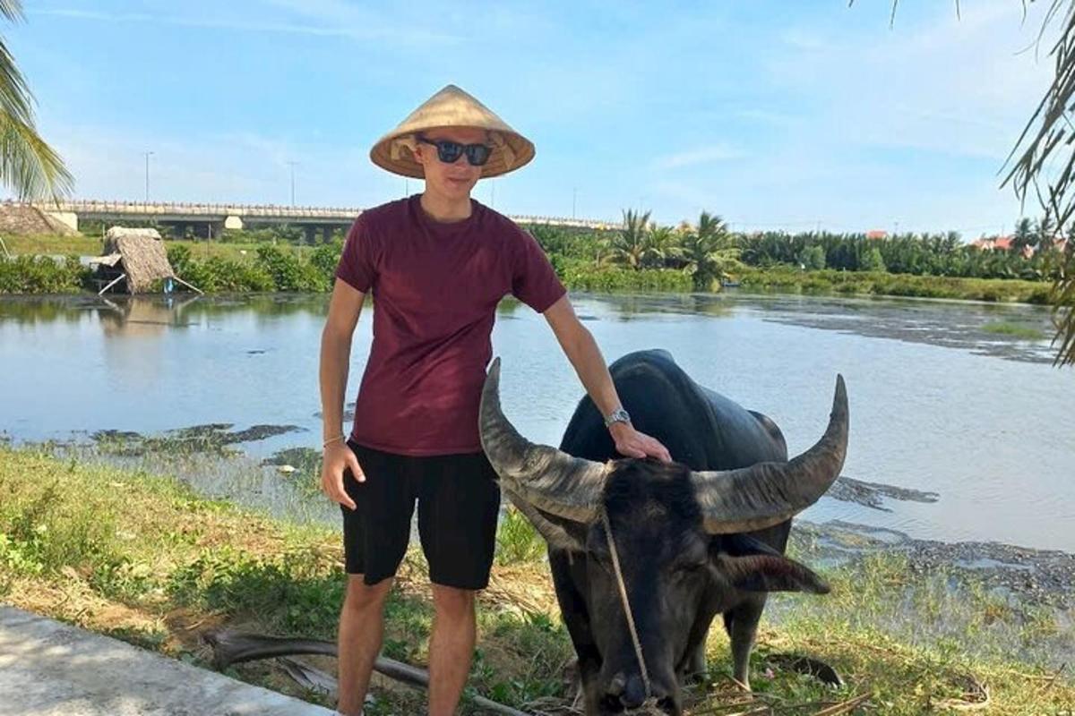 muž v klobouku stojící vedle krávy