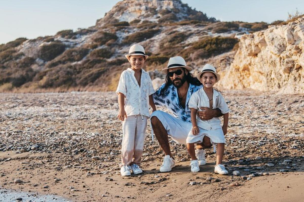 un uomo e due bambini seduti su una spiaggia