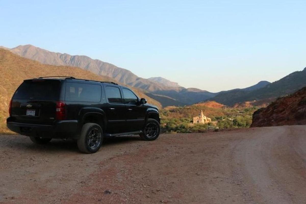 a black suv parked on the side of a dirt road