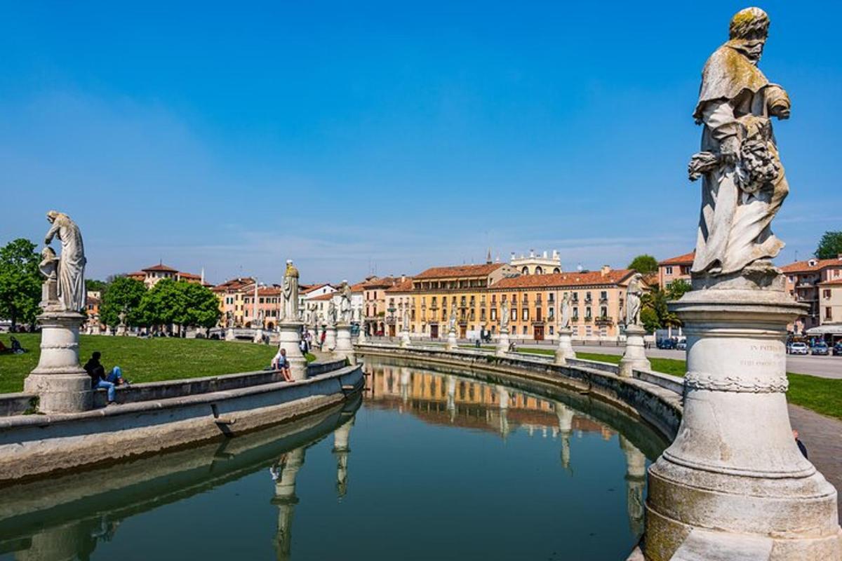 una statua accanto a uno specchio d'acqua con edifici