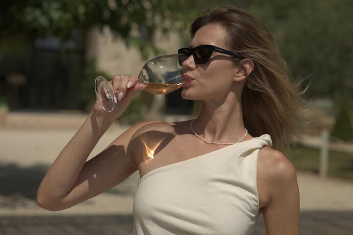 una donna con occhiali da sole che beve un bicchiere di vino