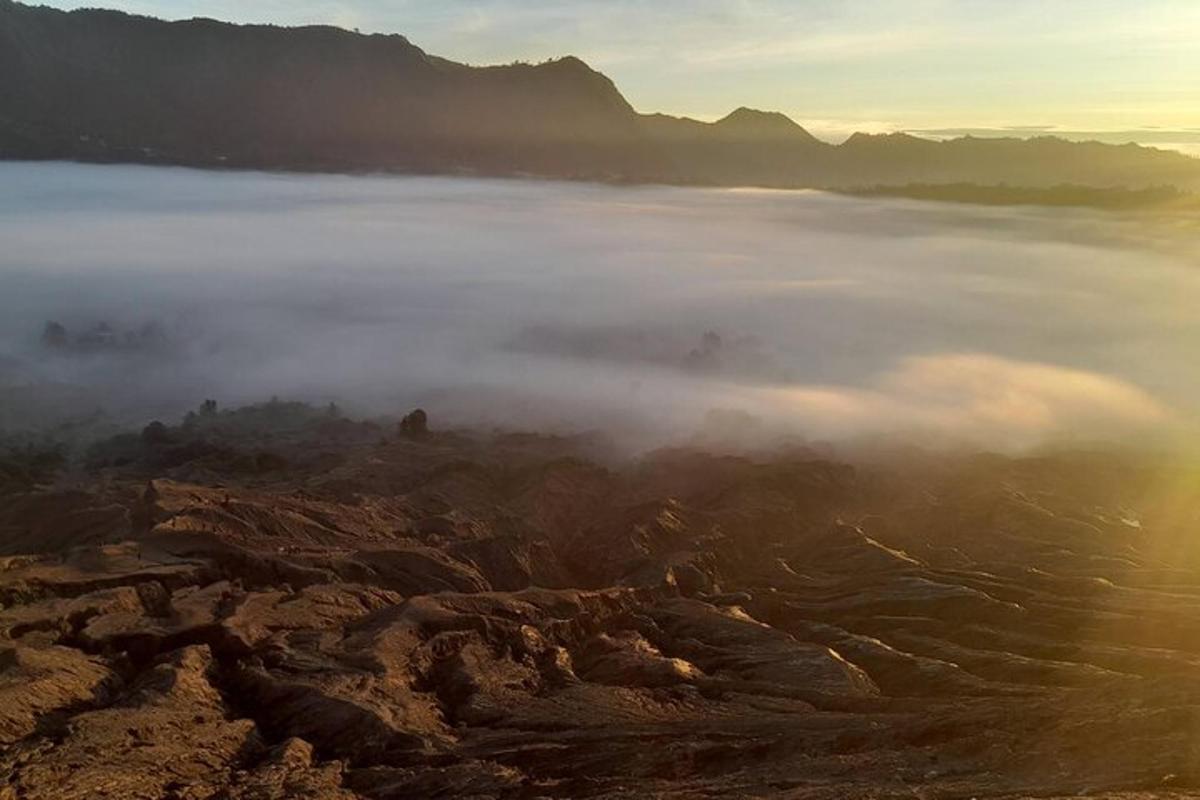 Útsýni yfir þokukennt fjall með fjöllum í bakgrunni