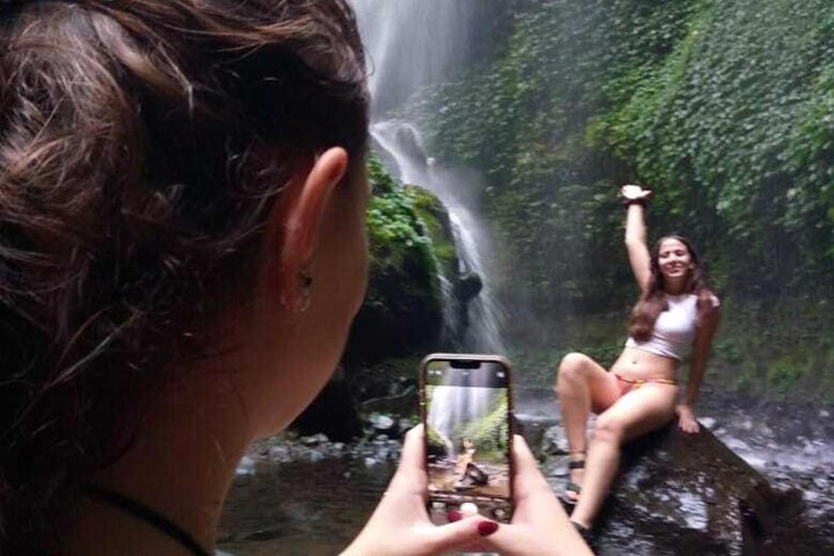 Kona tekur mynd af konu fyrir framan foss