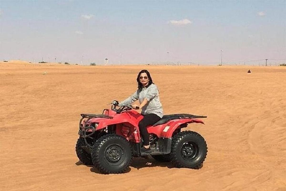 seorang wanita menunggang basikal quad di padang pasir