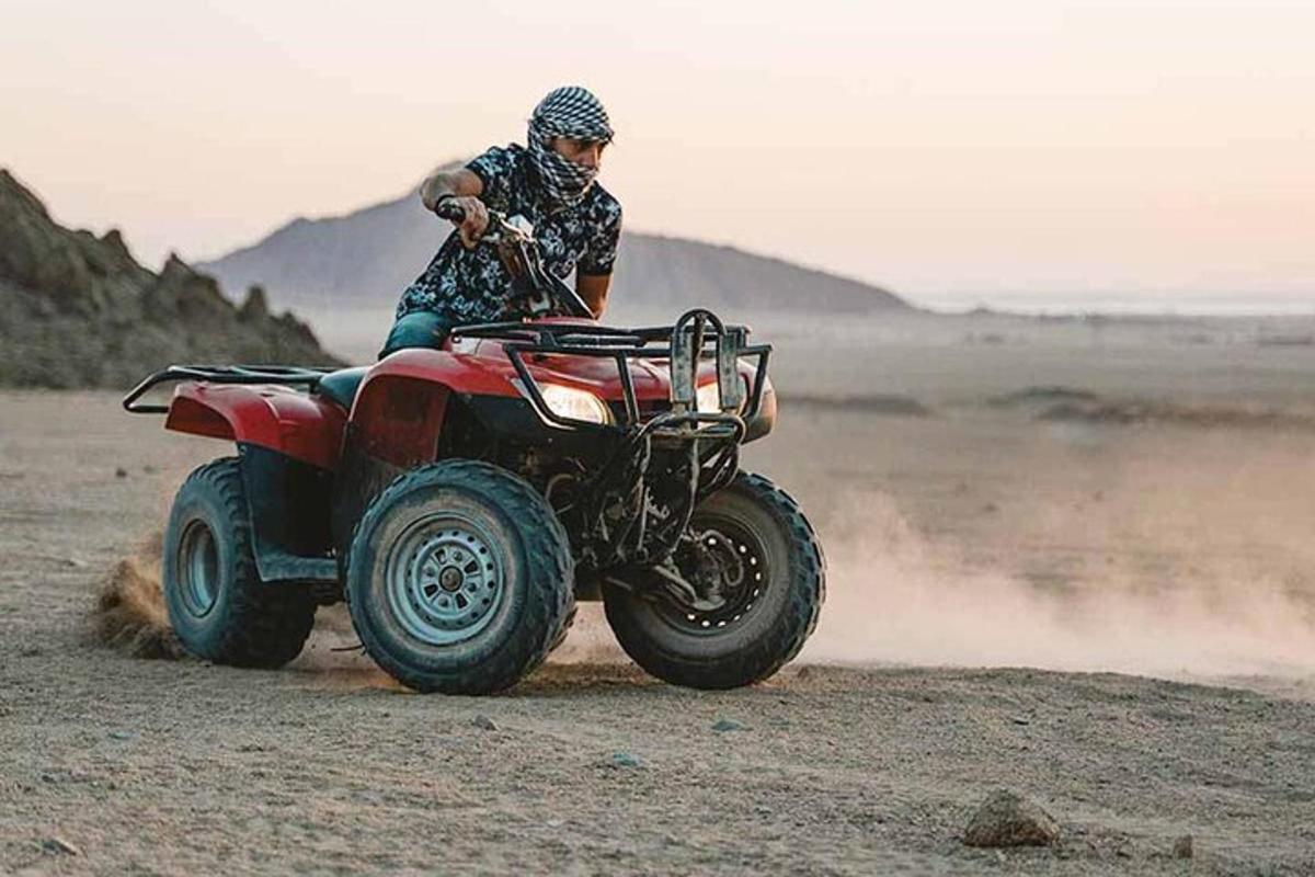 a man riding a four wheeler on a dirt road