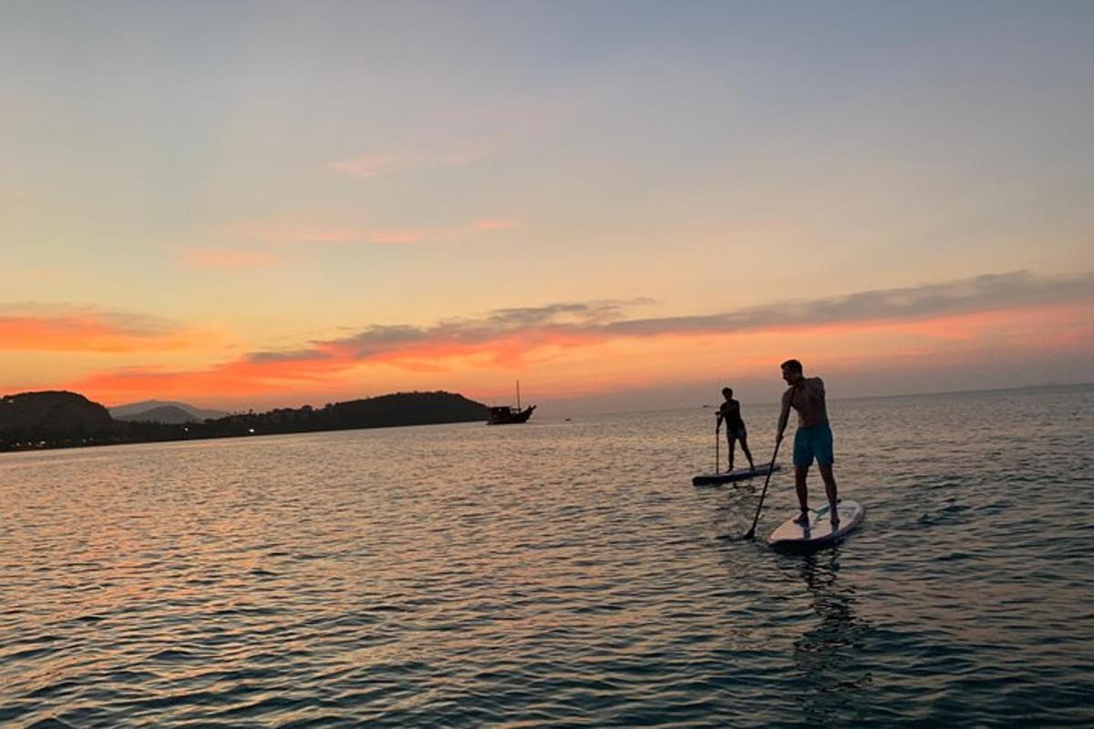 due persone su tavole da paddle in acqua al tramonto
