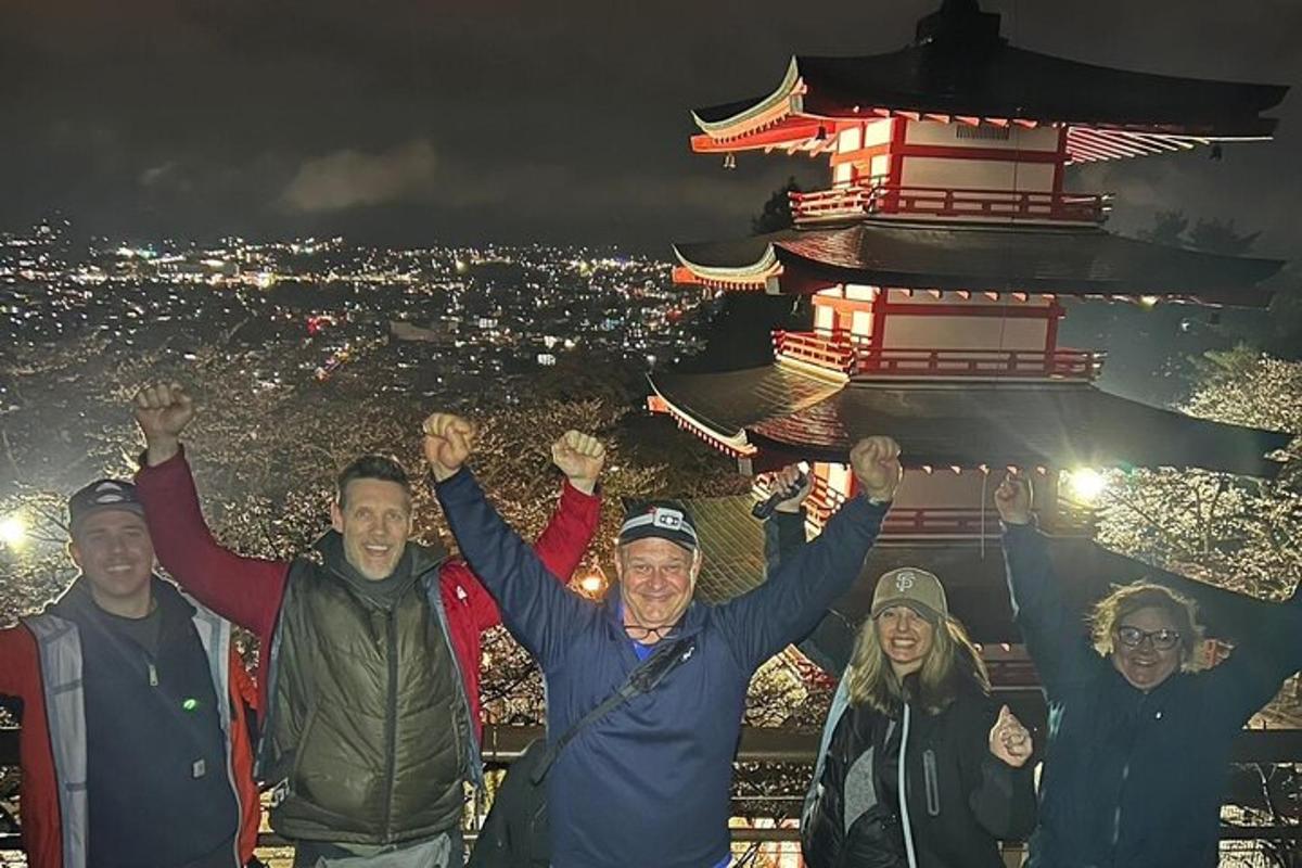 a group of people standing in front of a pagoda at night