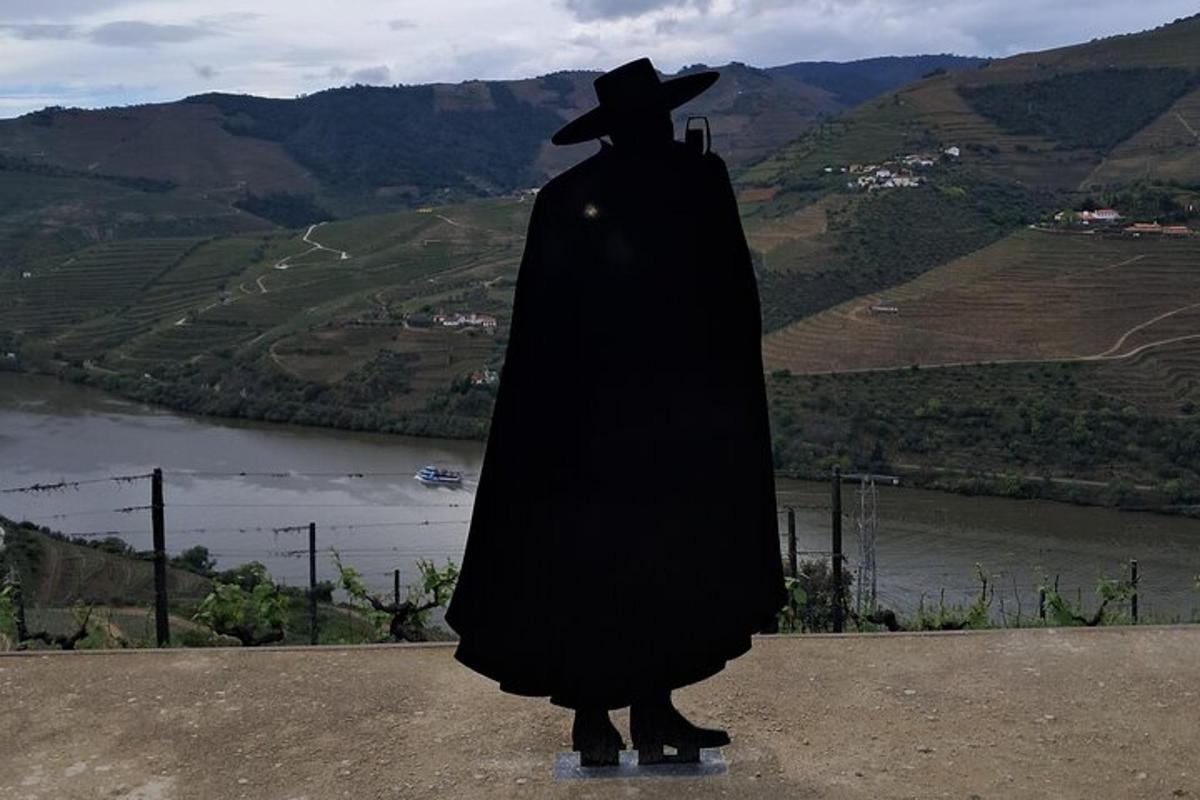 osoba v černém plášti a klobouku stojící na kopci