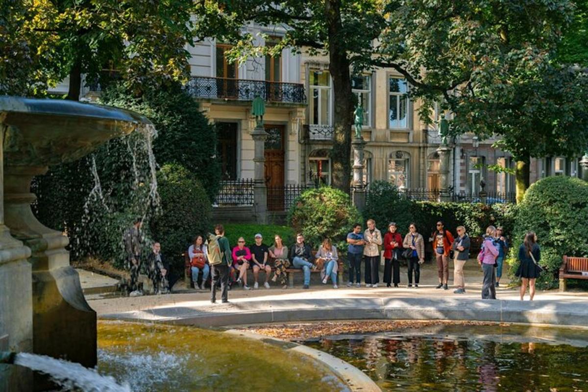 grupp inimesi, kes istuvad hoone ees purskkaevu ümber