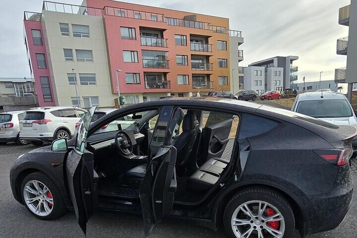 um carro preto com a porta aberta em um estacionamento