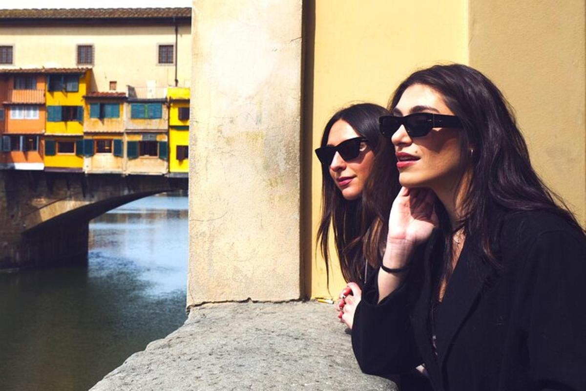 duas mulheres usando óculos de sol em pé ao lado de uma ponte