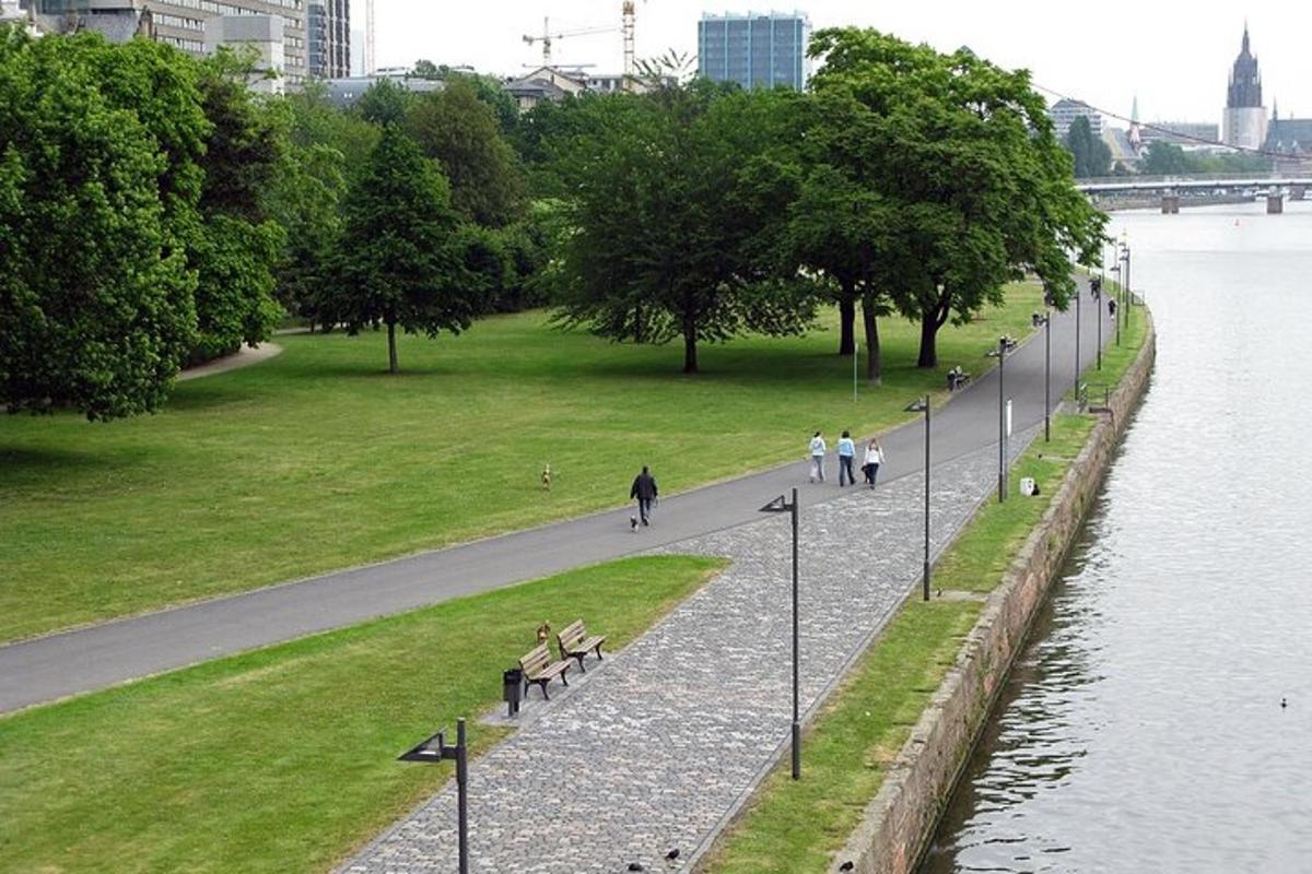 park s lidmi sedícími na lavičkách u řeky