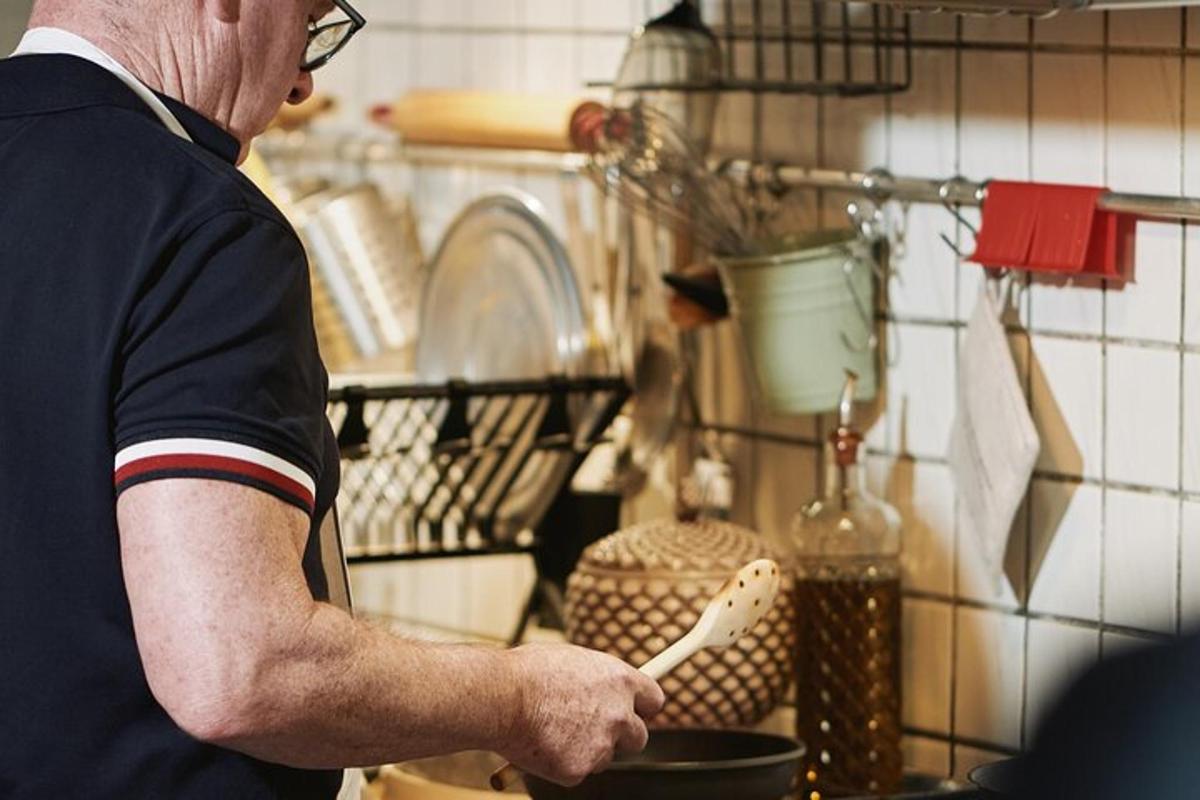 un home que sosté una espàtula en una olla a la cuina