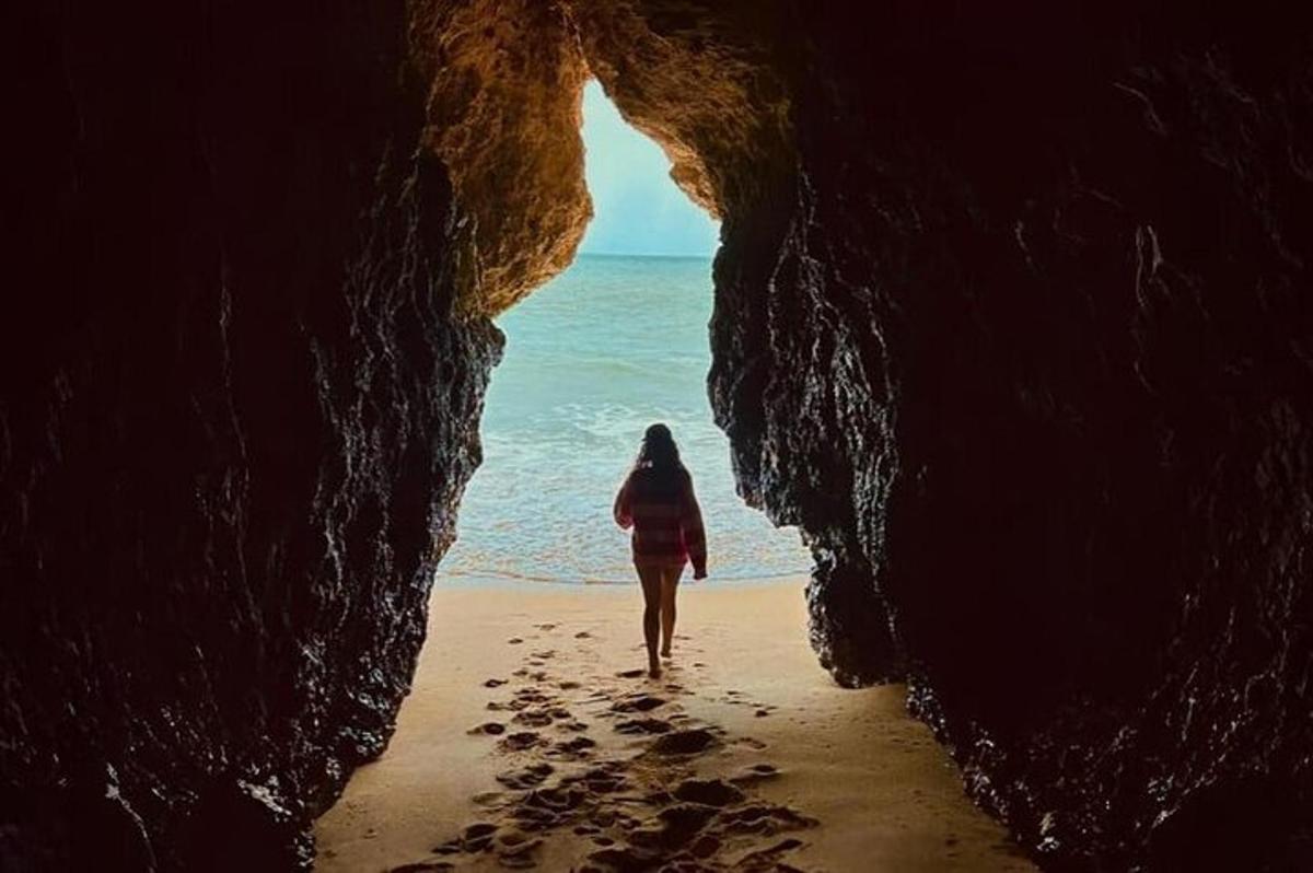 seorang wanita berjalan melalui gua di pantai