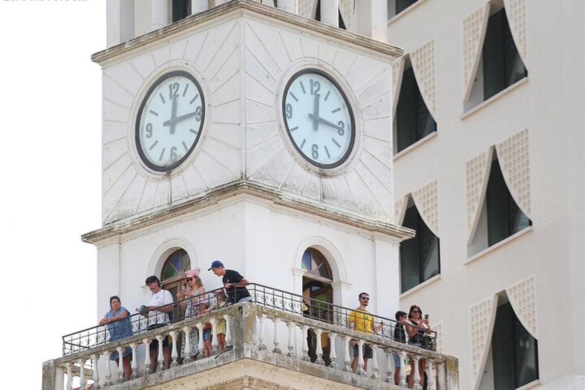 برج ساعة على مبنى مع أشخاص على شرفة