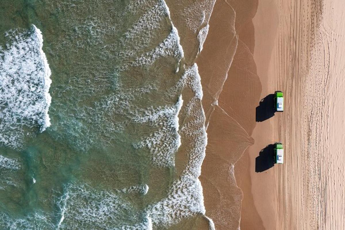 two cars parked on the beach next to the ocean
