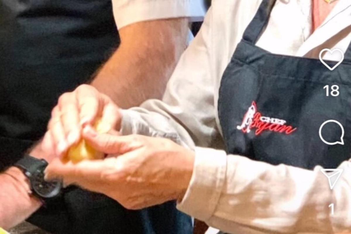 a man wearing an apron holding a hot dog