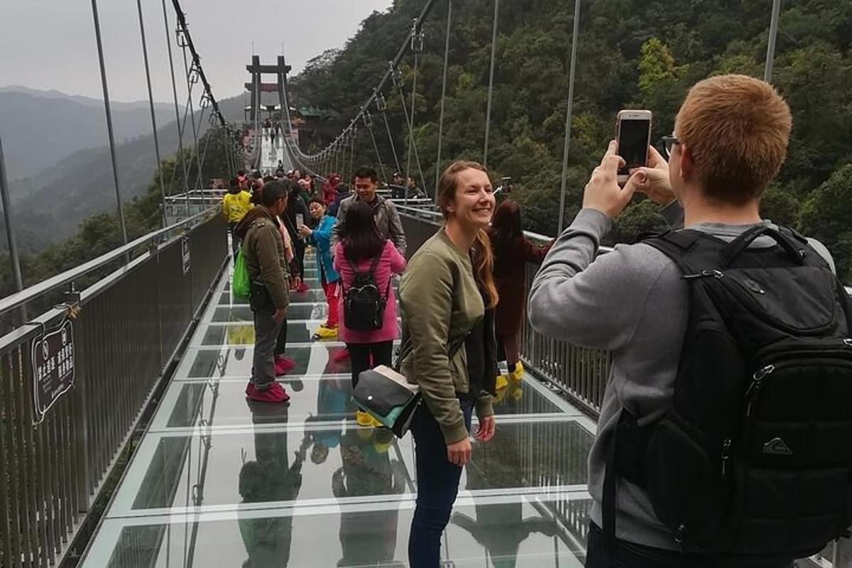 a man taking a picture of people on a suspension bridge