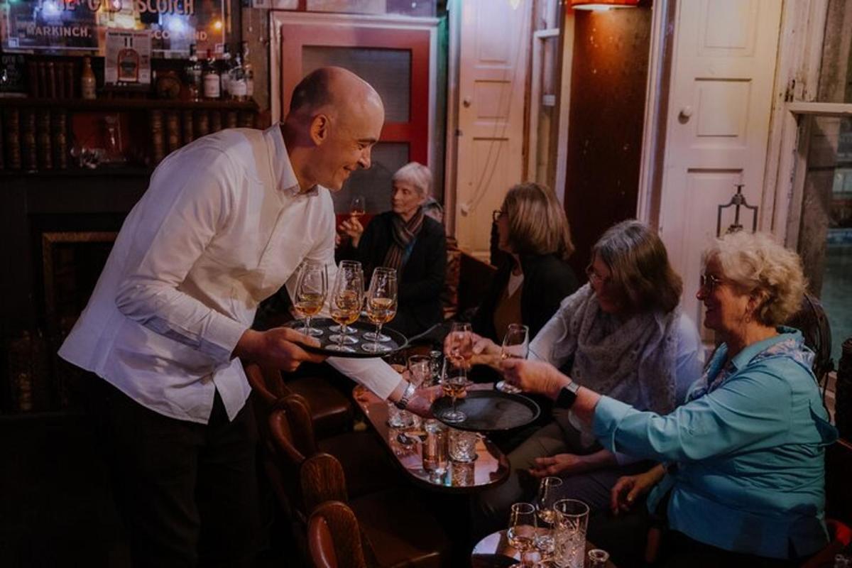 um homem segurando uma bandeja de copos sobre uma mesa