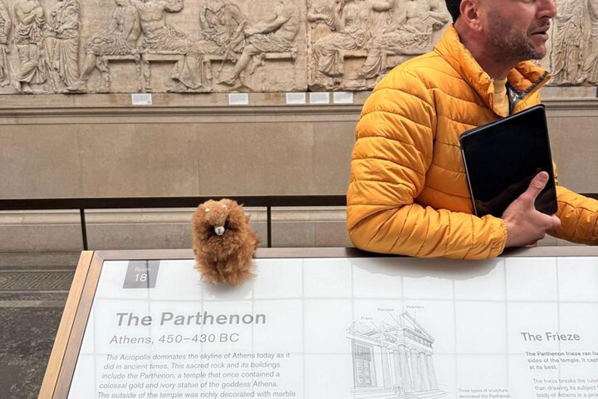 seorang lelaki berjaket kuning duduk di sebelah boneka haiwan