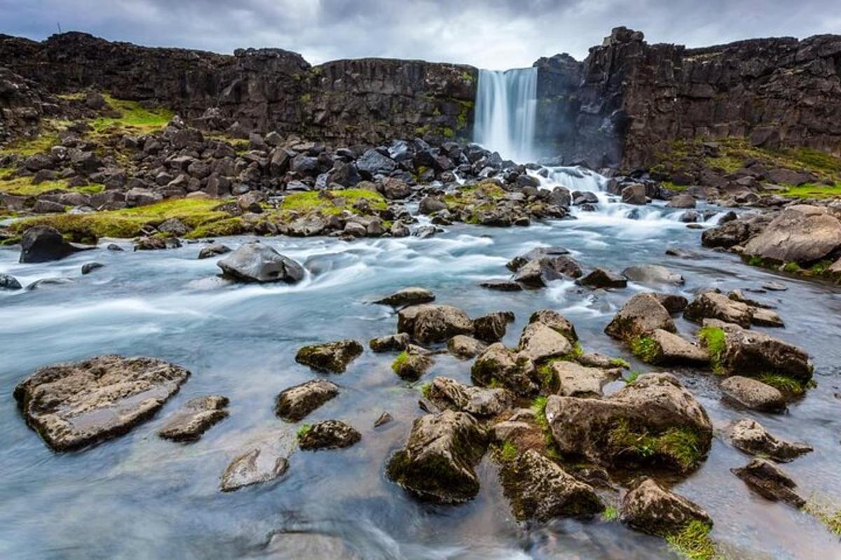 ein Wasserfall vor einem Fluss mit Felsen