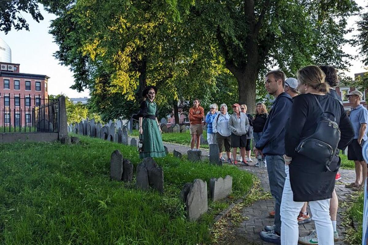 skupina lidí prohlížejících si sochu na hřbitově