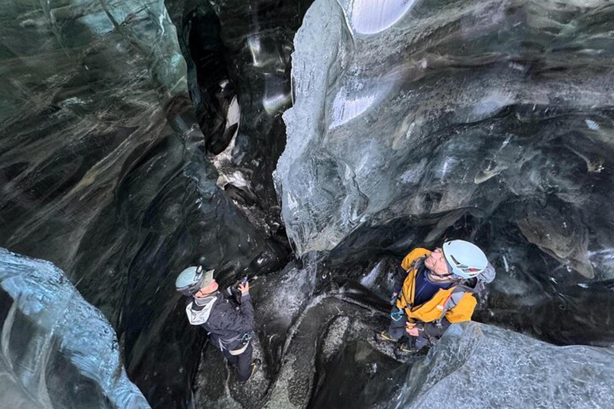 due persone stanno scalando una grotta di ghiaccio
