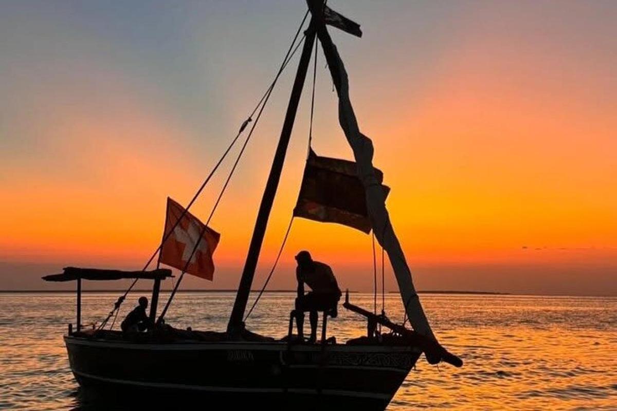 a man standing on a boat in the ocean at sunset