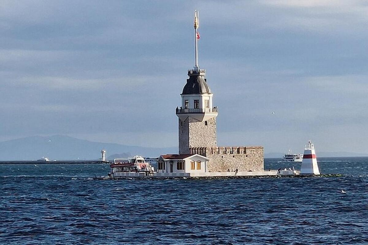 a lighthouse in the middle of the water with a boat