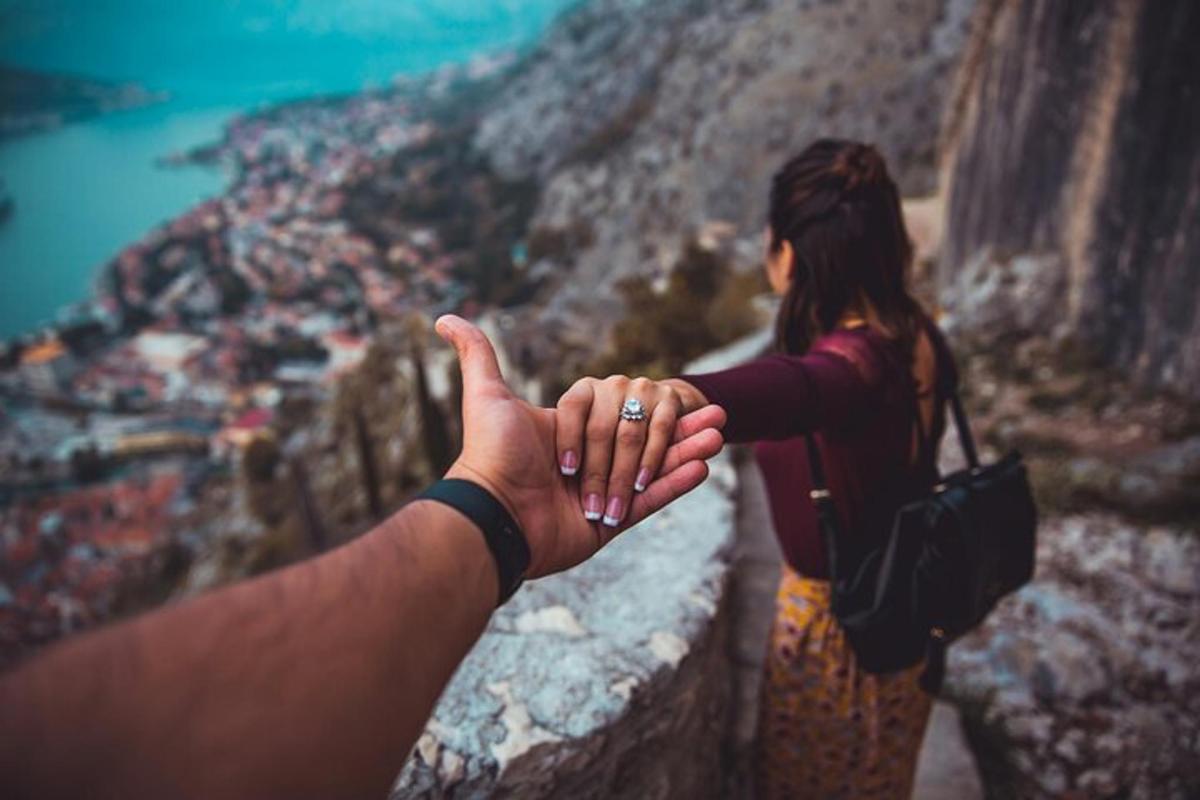 a man and woman holding hands while standing on a cliff