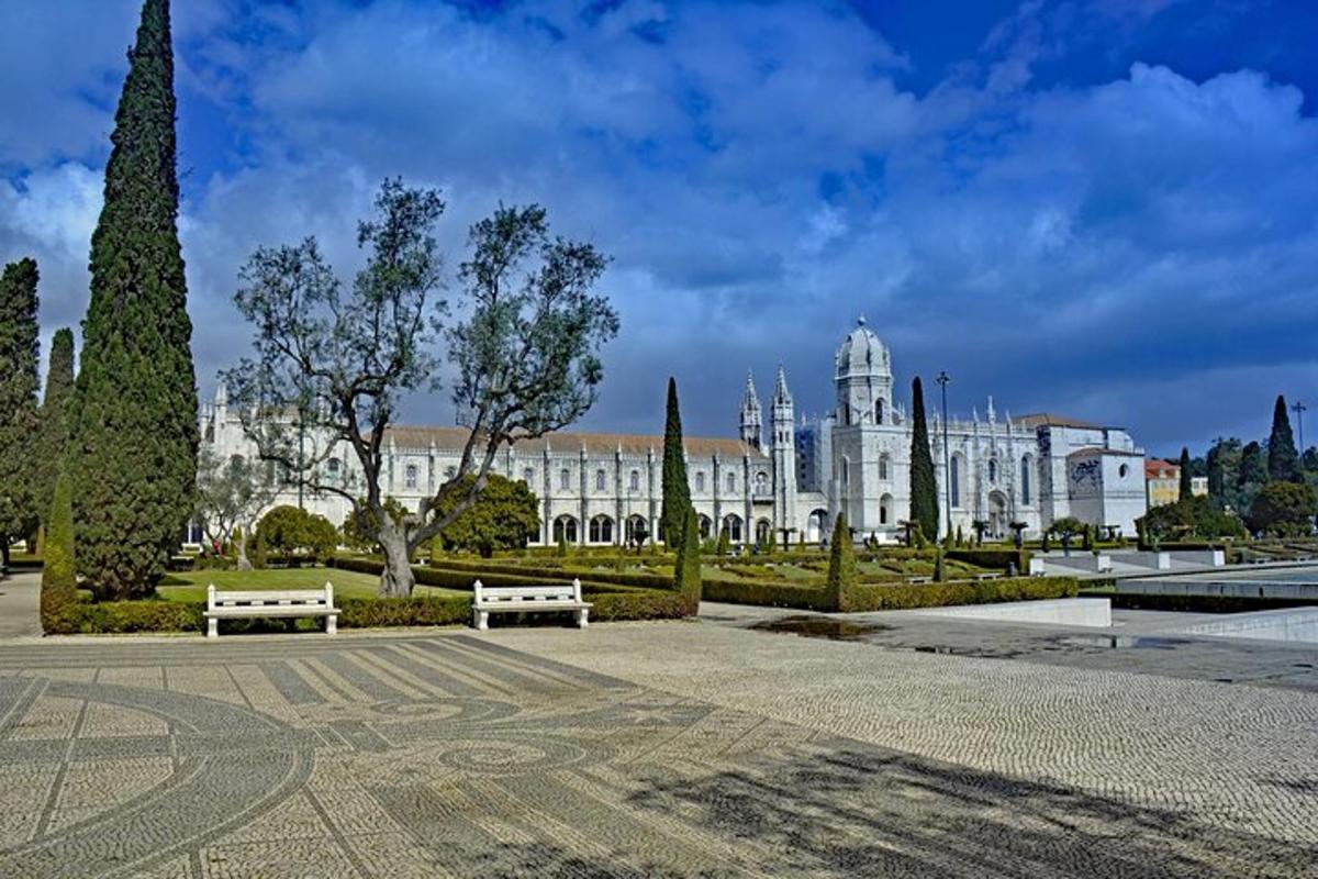 um grande edifício branco com dois bancos em um parque
