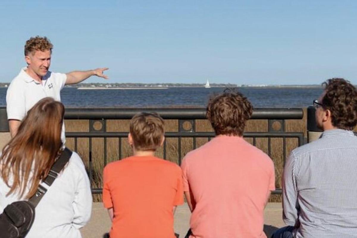 a group of people looking at a man pointing at the water