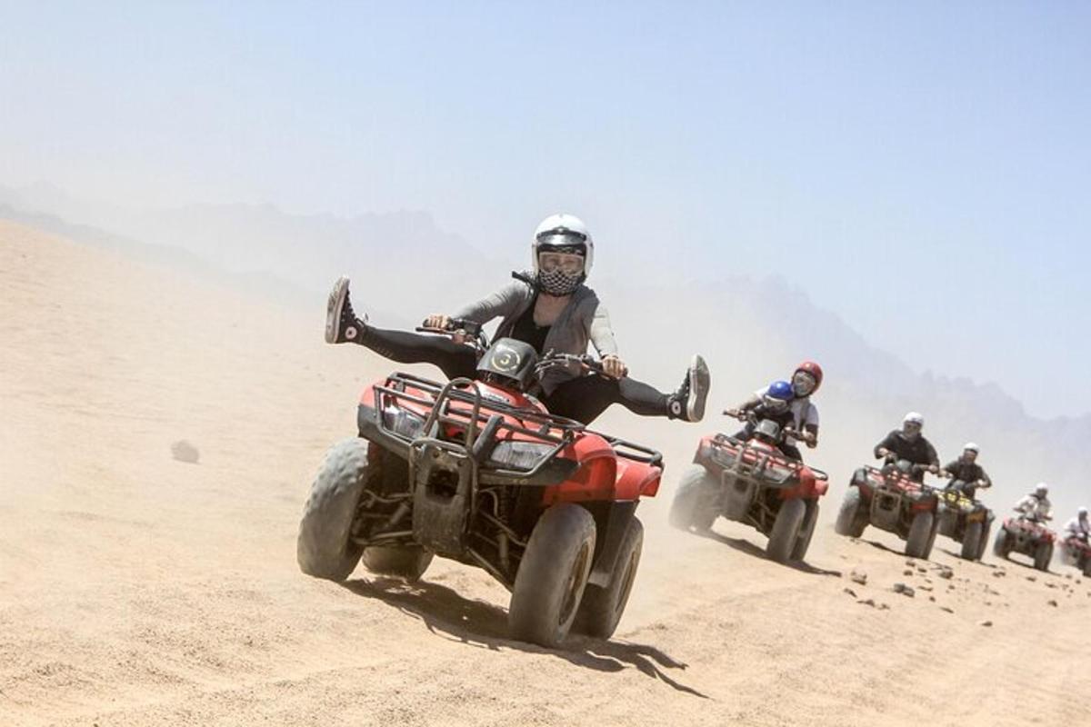 um grupo de pessoas andando de quadriciclo na areia
