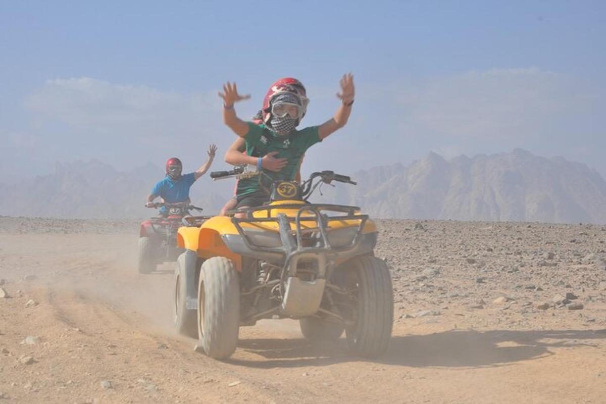 duas pessoas andando de quadriciclo no deserto